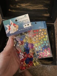 Using small gem stickers and aquarium rocks to help fill the treasure chest.
