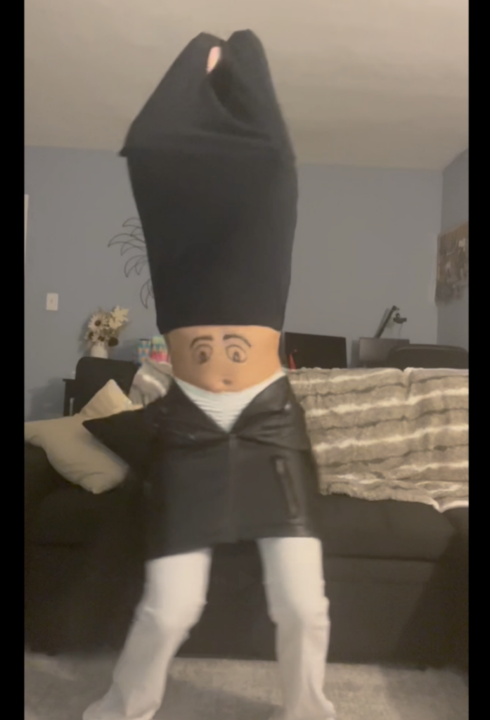 Someone with a face drawn on their stomach, a shirt covering their face and a jacket over their pants to make it look like their belly is the head.